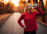 woman standing outside drinking from a water bottle